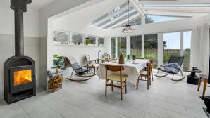 Una habitación amplia con chimenea, una mesa de comedor, sillas y un gran ventanal con vistas a un jardín.