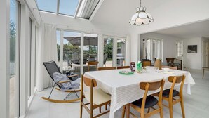 Un comedor con una mesa preparada para cuatro personas, una mecedora y vistas del patio exterior.
