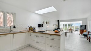 Una cocina moderna con armarios blancos, una isla grande y un tragaluz.