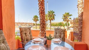 Tavolo da pranzo imbandito per due con vista sulle palme e un parcheggio sullo sfondo.