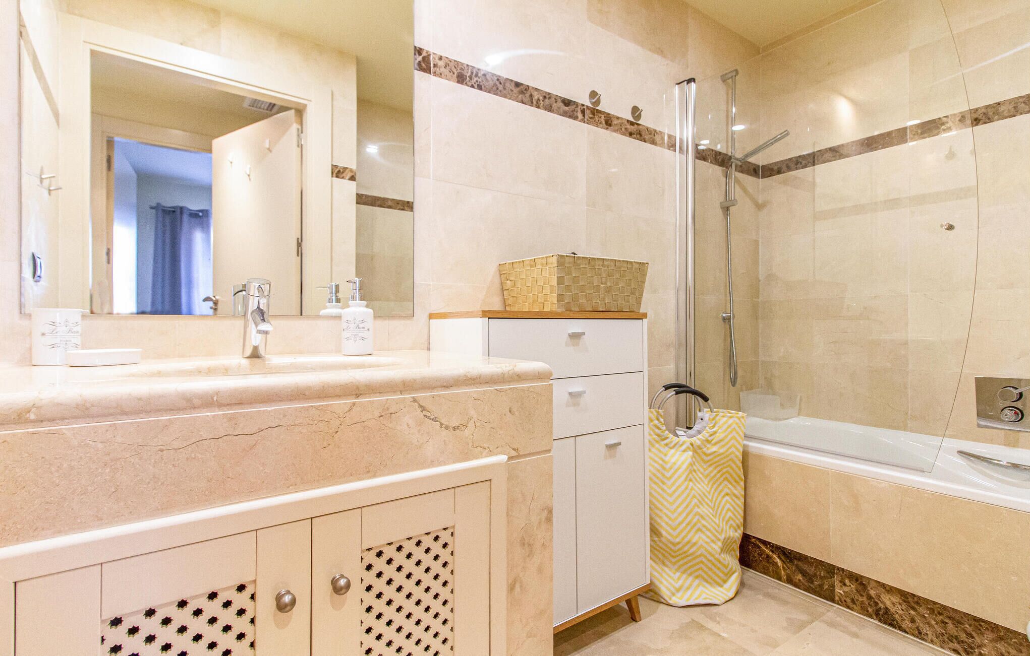 A modern bathroom with a marble vanity, a glass shower enclosure, and a bathtub.