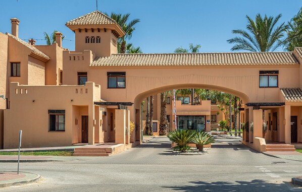 A hotel entrance with a large archway, palm trees, and a clear sky. - Stunning apartment in Los Alcazares (Los Alcazares)