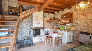 Eine rustikale Küche mit Steinwand, Holzbalken, Kamin und einer Holztreppe.