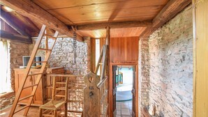Ein rustikales Holzhaus-Interieur mit einer Steinwand, einer Holztreppe und Blick ins Badezimmer.