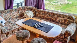 Une pièce avec un canapé à motifs floraux, une table basse en bois et une vue sur un espace verdoyant par la fenêtre.