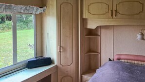 Une chambre avec une fenêtre, un lit, une étagère et un placard.