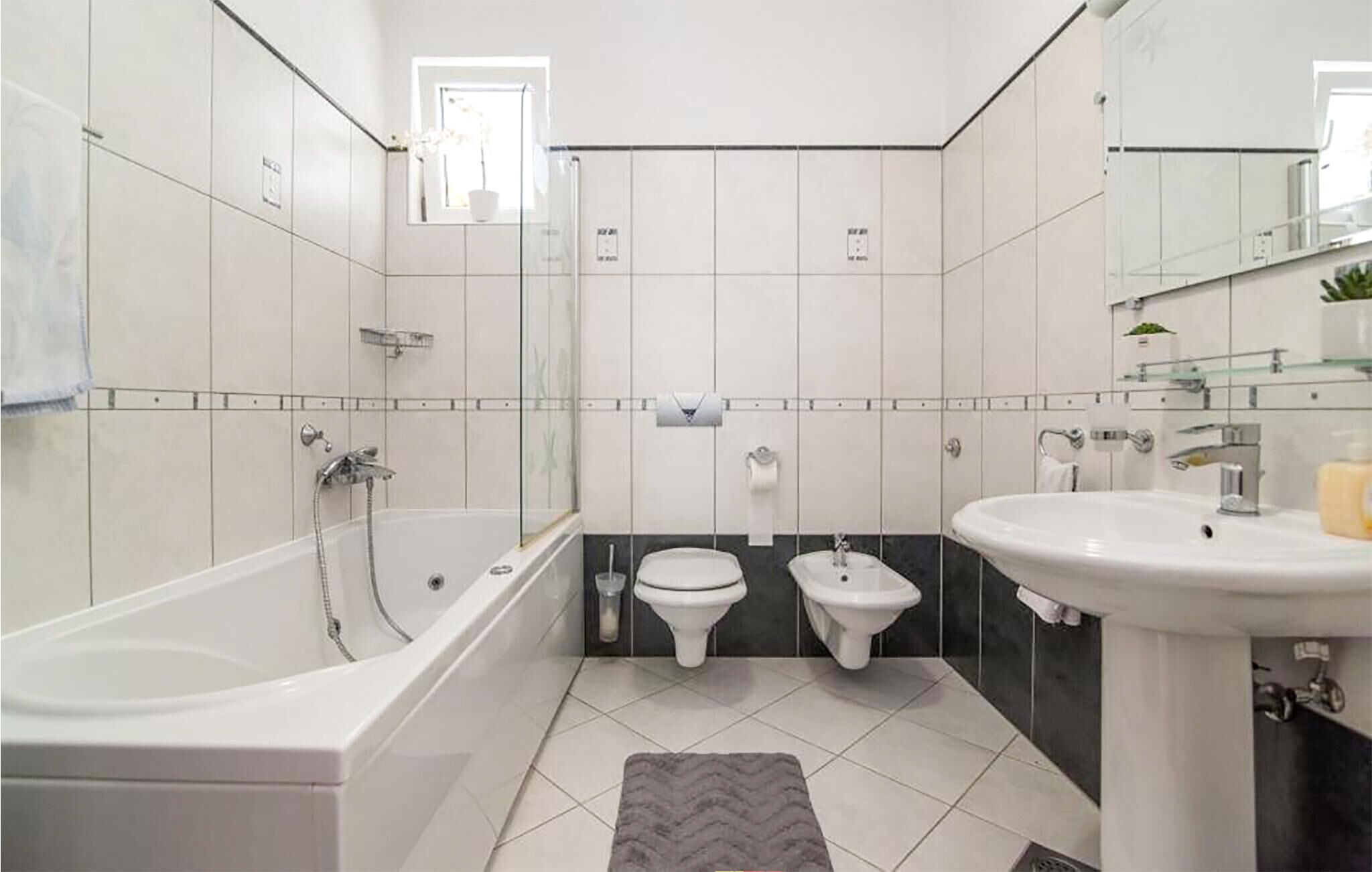 Ein modernes Badezimmer mit einer Badewanne, zwei Toiletten, einem Waschbecken und einer Dusche.