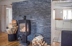 A cozy room with a stone wall, a wood-burning stove, and a stack of firewood. - Stunning home in åseda with kitchen (Åseda)