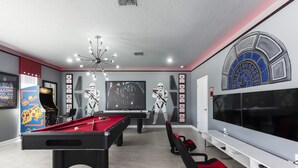 Een moderne kamer met een pooltafel, een grote flatscreen-tv en decoraties met het thema Star Wars.