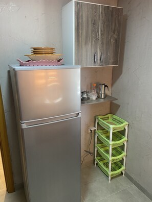 Kitchen area with refrigerator, cabinet, and storage unit for a convenient stay.
