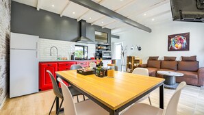 A modern kitchen with red cabinets, a wooden dining table, and a black range hood.