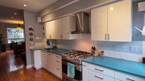 A modern kitchen with white cabinets, a stainless steel stove, and a blue countertop.
