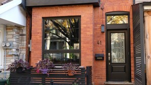 A two-story building with a black front door, large windows, and a brick facade.