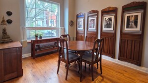 A dining area with a wooden table and chairs, a bench, and a window with a view of buildings outside.