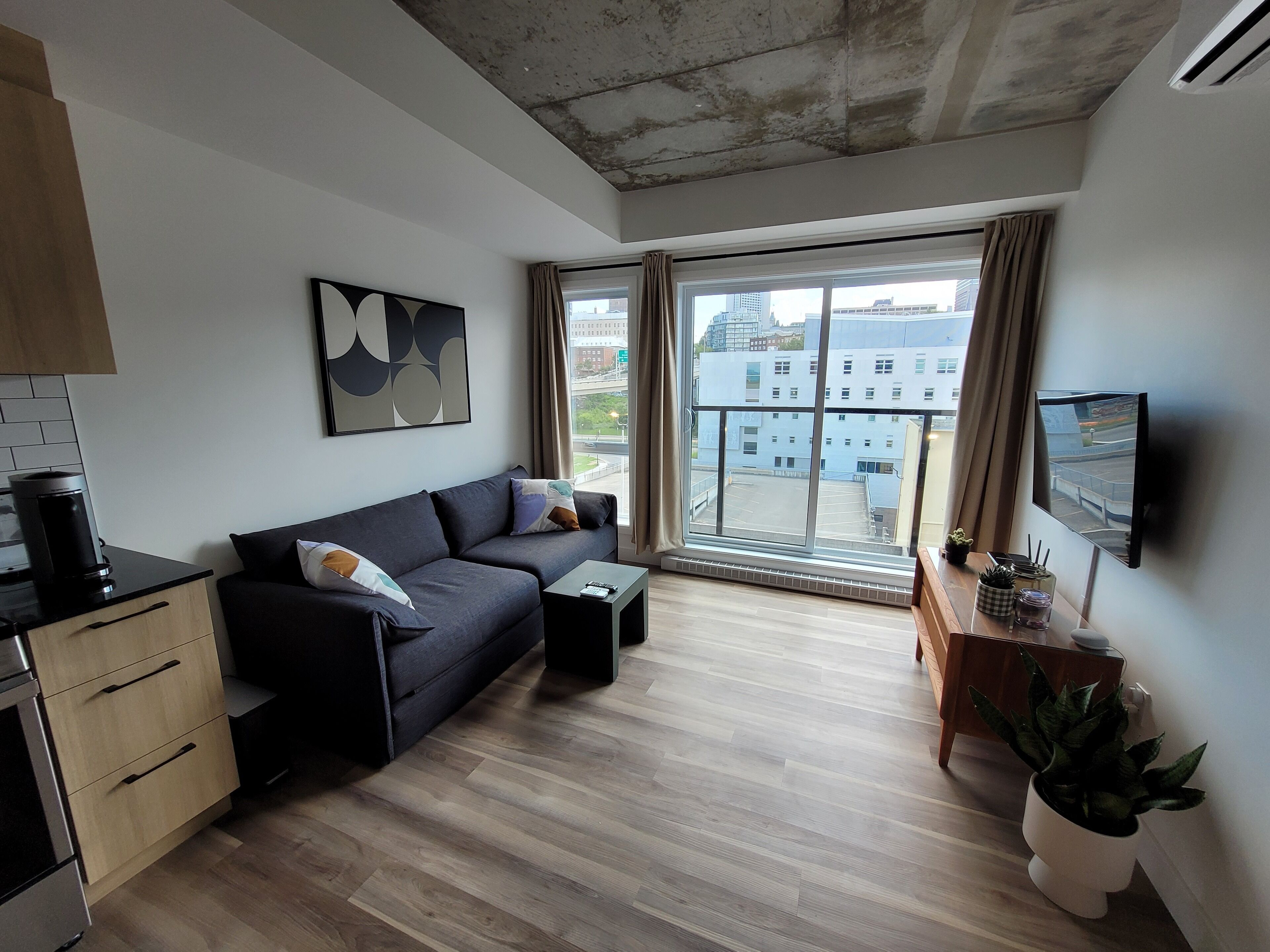 Een moderne woonkamer met een bank, salontafel en een aan de muur bevestigde televisie.