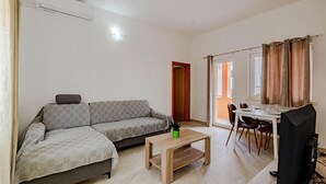 A living room with a sofa, a coffee table, a dining table with chairs, a TV, and a sliding glass door leading to an outdoor area. - Awesome home in Korcula with WiFi (Korcula)