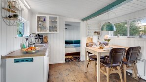 A compact kitchen with a sink, countertop, and cabinets. There is a dining area with a table and chairs. - 2 bedroom nice home in Aabenraa (Aabenraa)