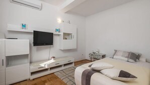Un dormitorio moderno con cama, televisión, armario y mesita de noche.