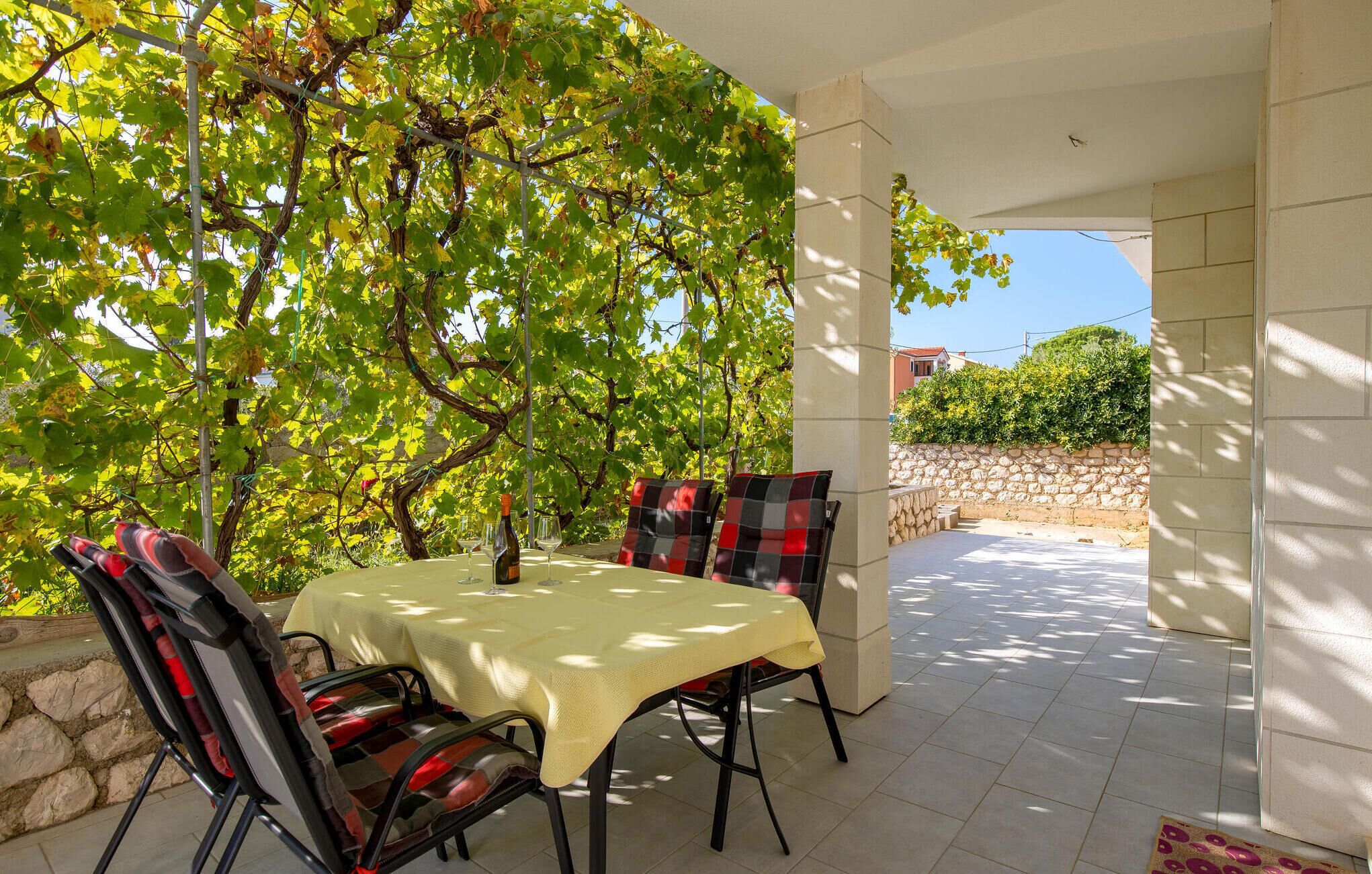 Un espace de restauration en plein air avec une table et des chaises, une bouteille de vin et une vue sur un vignoble.