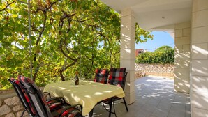 Un espacio de comedor al aire libre con una mesa y sillas, una botella de vino y vistas a un viñedo.