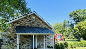A stone house with a covered porch and a metal roof. - Historic Schoolhouse on Winery Row (Purcellville)