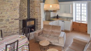 Una sala de estar acogedora con chimenea, un comedor con mantel a rayas y una cocina con armarios de madera y ventana.