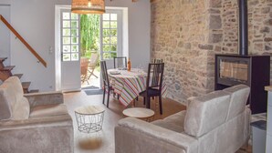 Una sala de estar acogedora con pared de piedra, chimenea y comedor con mantel a rayas.