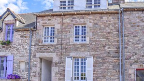 Un edificio de piedra con varias ventanas, una puerta y un pequeño balcón con flores.