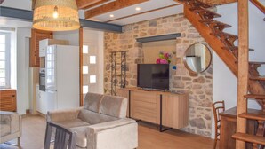 Una sala de estar acogedora con sofá, televisión y pared de piedra.