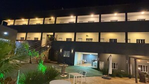 Un edificio de varios pisos con balcones, una escalera y un patio con mesas y sillas al aire libre.