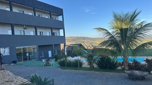 Un edificio moderno con piscina, mobiliario exterior y palmeras.