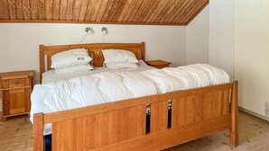 A wooden bed with white bedding in a room with a sloped ceiling and wooden flooring. - Pet friendly home in Lidköping (Lidköping)