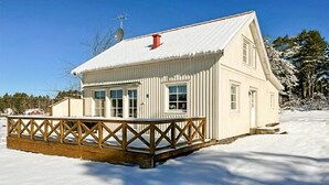 A white wooden house with a snow-covered roof and a wooden deck. - Pet friendly home in Lidköping (Lidköping)