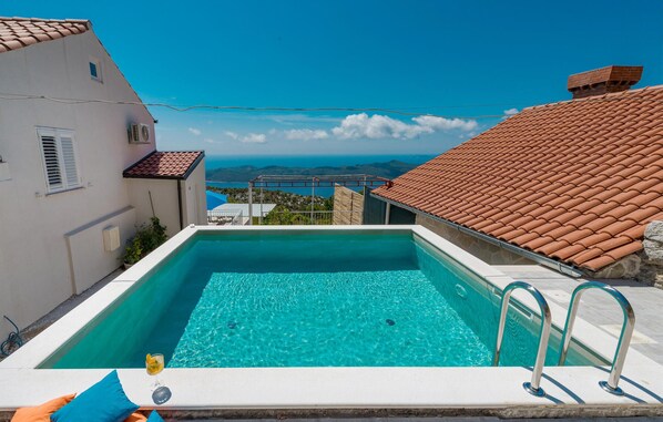 Une piscine rectangulaire à l’eau d’un bleu cristallin, entourée d’une terrasse blanche.