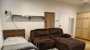 Une chambre à coucher comprenant un lit, un canapé, une petite table, une armoire et un ventilateur de plafond.
