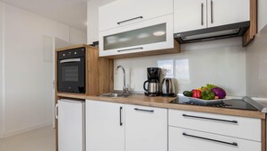 Eine moderne Küche mit weißen Schränken, einem Backofen, einer Kaffeemaschine und einem Spülbecken.