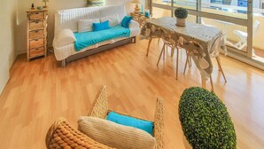 Ein modernes Wohnzimmer mit einer Couch, einem Esstisch und einer kleinen Zimmerpflanze.
