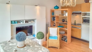Ein modernes Wohnzimmer mit Kamin, einem Esstisch mit dekorativer Dekoration, einem Korbstuhl und eingebauten Holzbögen mit Küchengeräten.