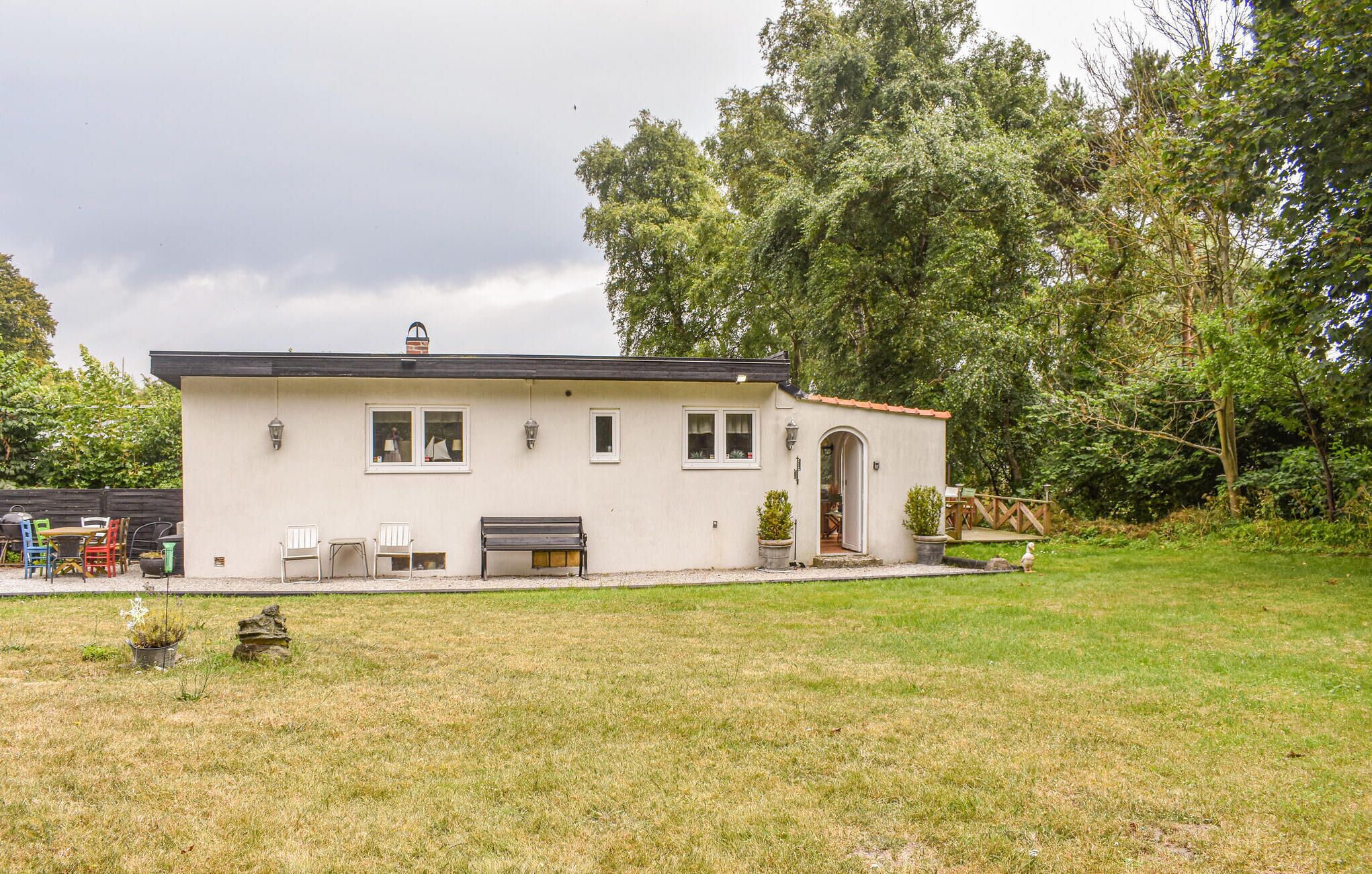 Een gelijkvloers huis met plat dak, een voortuin en een kleine aangebouwde garage.