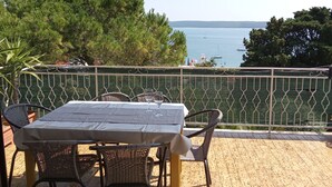 Un espace extérieur aménagé pour les repas, avec une table et des chaises, offrant une vue sur un plan d’eau et des arbres.