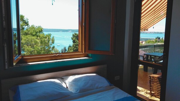 Une chambre avec une grande fenêtre donnant sur un paysage magnifique, avec des arbres et de l’eau.
