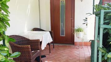 A patio area with a table and chairs, a door, and potted plants.
