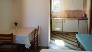 Een compacte keuken met een eethoek, een klein raam en een kitchenette.