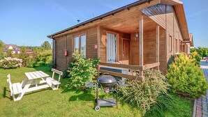 A wooden cabin with a porch, a barbecue grill, and a picnic table in the yard. - 2 bedroom beach front home in Wicie (Wicie)