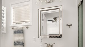 Un baño con lavamanos blanco, un espejo, toallero, inodoro y suelo de madera.