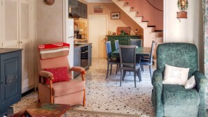 A cozy living room with a dining area, a staircase leading to a kitchen, and a green armchair.