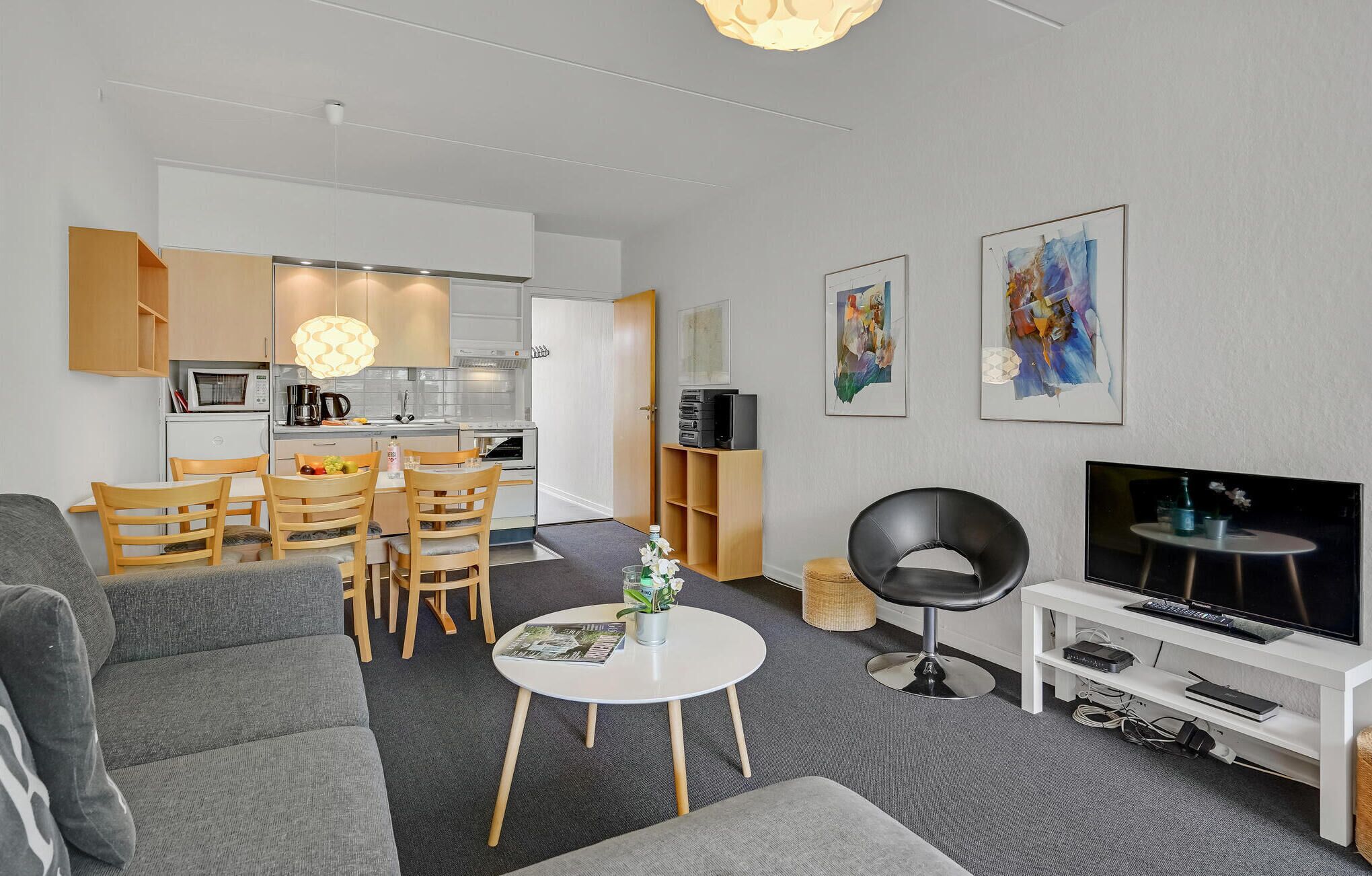 A modern living room with a grey sofa, a round coffee table, and a TV on a white stand.