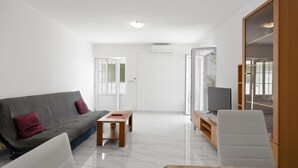 A modern living room with a grey sofa, a small wooden table, a white armchair, and a TV on a wooden stand. - Nice apartment in Murter with WiFi (Murter)