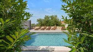 A swimming pool with lounge chairs and a stone wall in the background. - Nice apartment in Murter with WiFi (Murter)