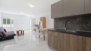A modern kitchen with a dark countertop and wooden cabinets, a built-in sink, and a sliding glass door leading to a dining area with a table and chairs. - Nice apartment in Murter with WiFi (Murter)